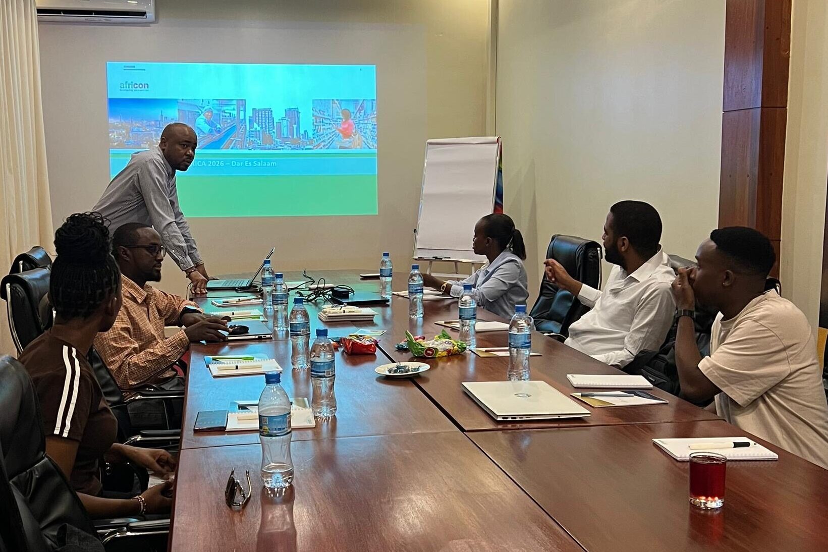 Ein africon-Teammitglied leitet eine Workshop-Session in Daressalam; Kollegen sitzen um einen Konferenztisch